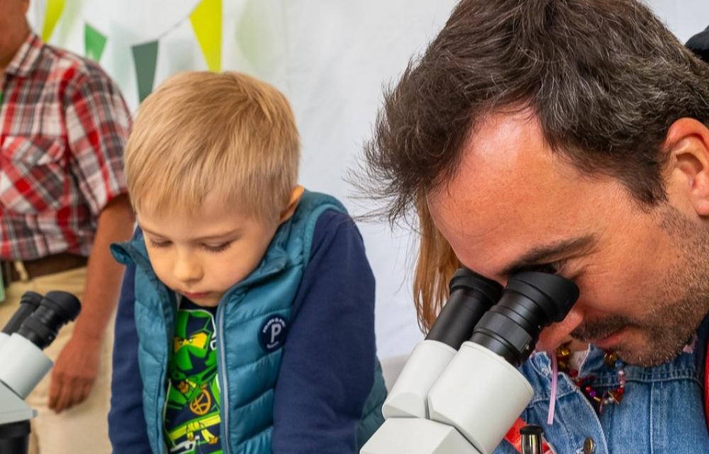 Laps, tema kõrval mees, kes uurib mikroskoobist